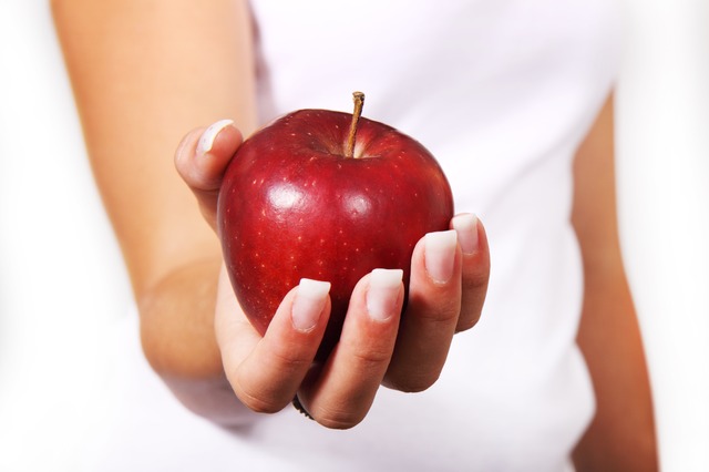 kobieta trzymająca w ręku czerwone jabłko.